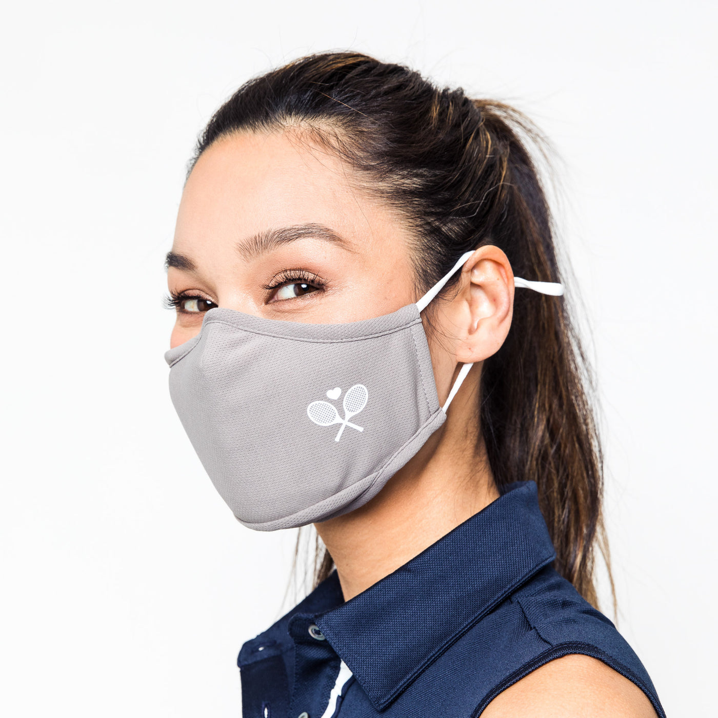 woman wears light grey face mask with white crossed racquets printed on one side