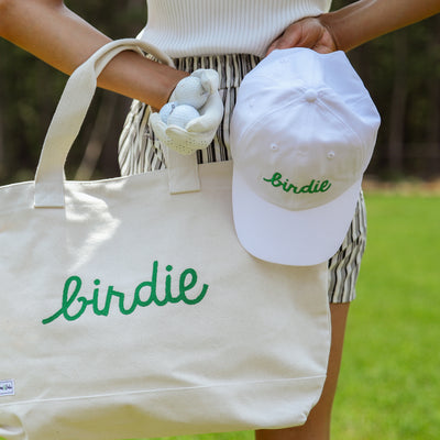 White baseball hat with the word birdie embroidered on the front in a green cursive font