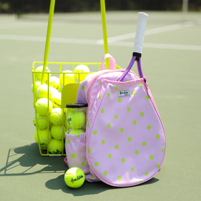 Kids tennis backpack with front pocket to hold tennis racquet. Bag is printed with a pink and white striped pattern and repeating tennis balls on the stripes.