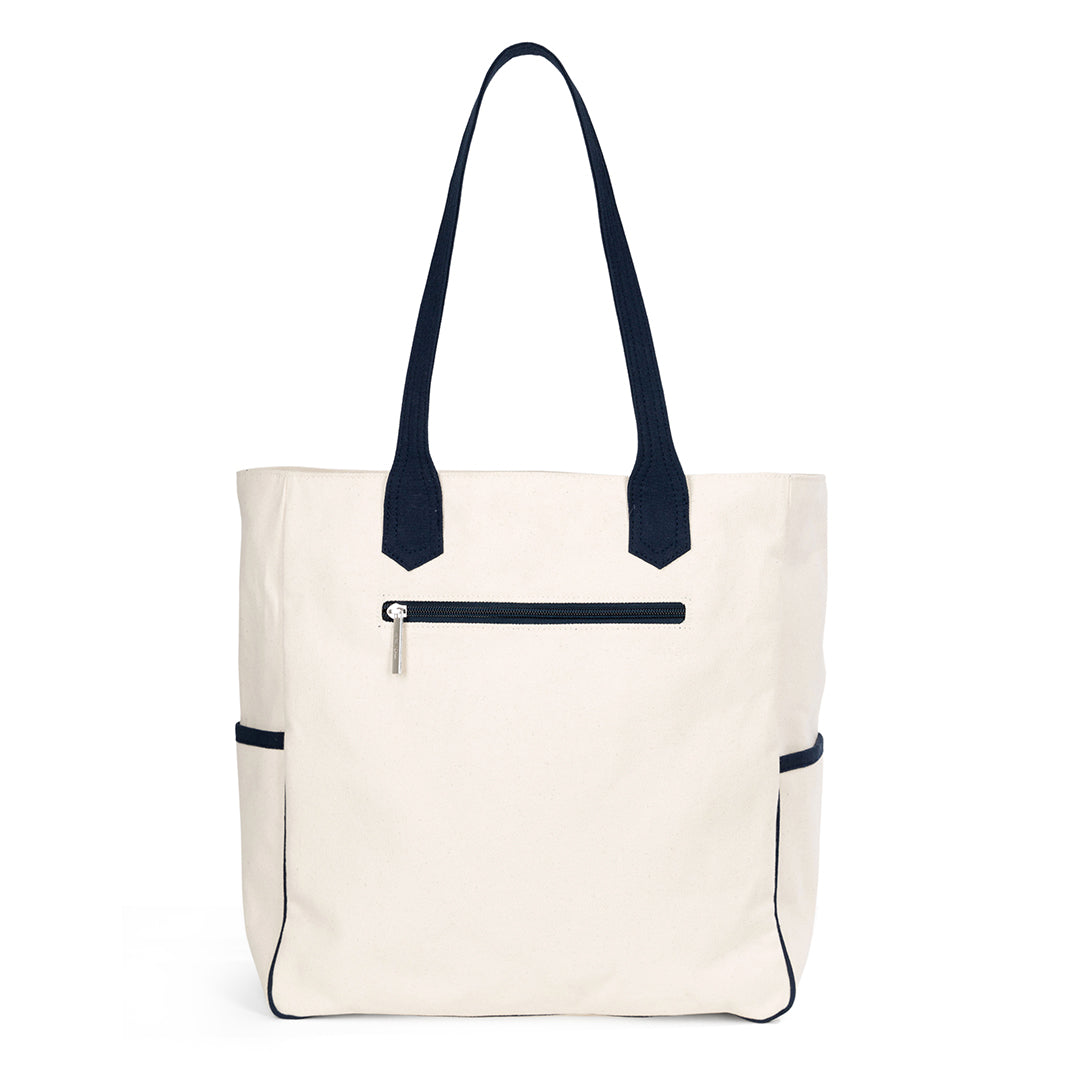 Back view of canvas tote with navy trim and handles. There is a zipped pocket on the back