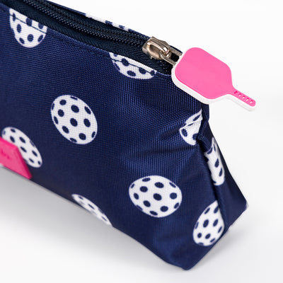 Side view of navy nylon small makeup pouch. Pouch has white pickleball printed on it and a hot pink pickleball paddle zipper.