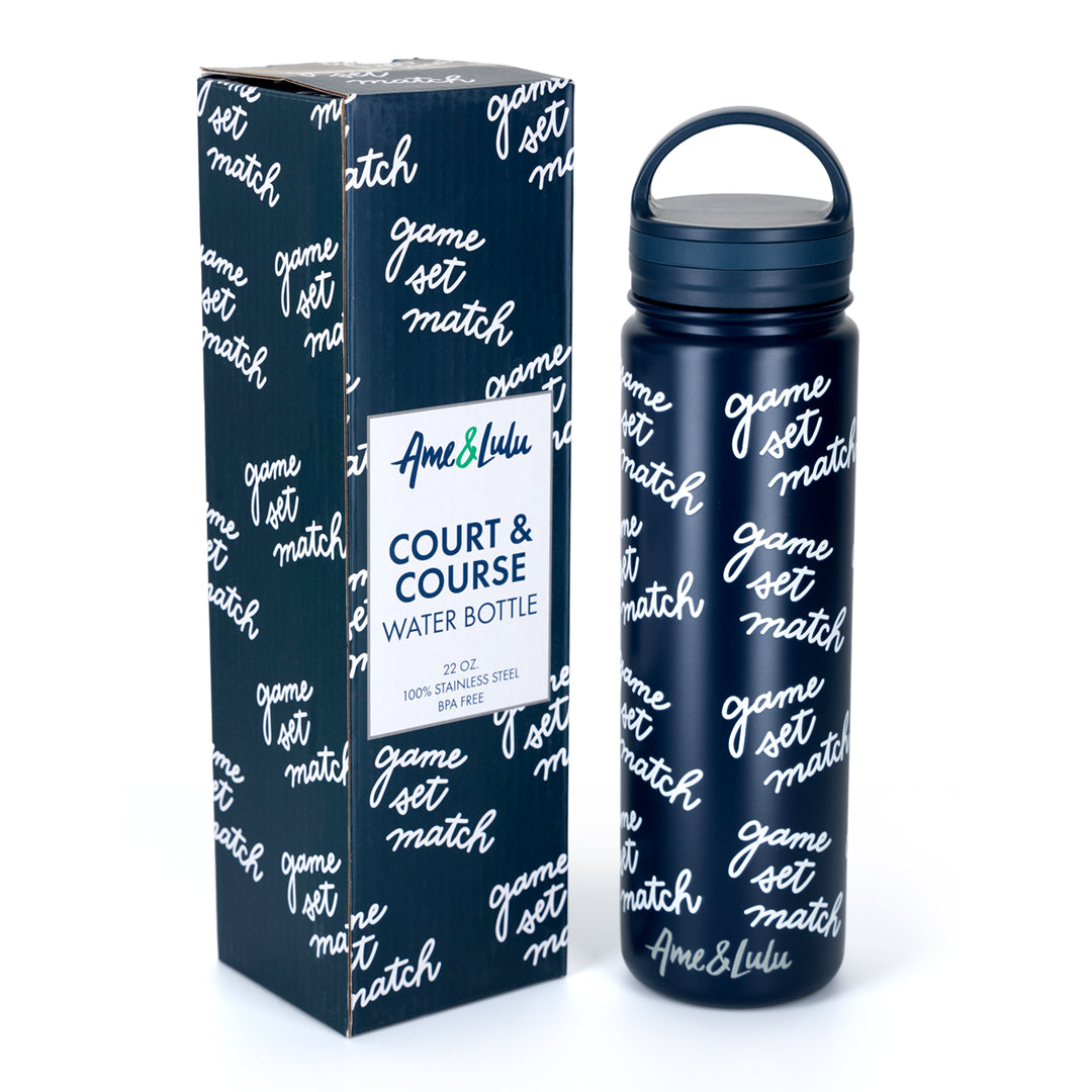Navy water bottle with game set match text repeating print on bottle. Next to bottle in matching box packaging. 