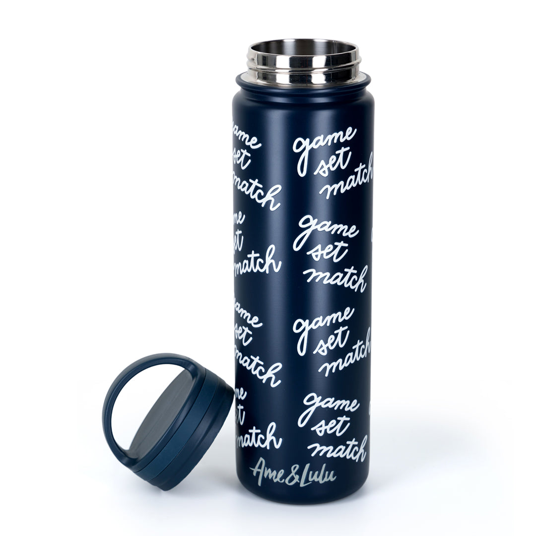 Navy water bottle with game set match text repeating print on bottle. Top is off of bottle and next to it