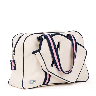 Side view of natural canvas pickleball tote with navy trim and navy and pink straps and handles.