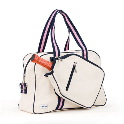 Side view of natural canvas pickleball tote with navy trim and navy and pink straps and handles.