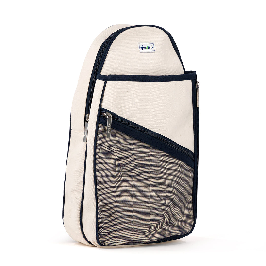 side view of Hamptons pickleball sling bag. Bag has front mesh pocket and slip pocket on front to hold pickleball paddles. Bag has navy trim and navy and white striped straps. Bag has adjustable straps to be worn as a backpack or a crossbody.