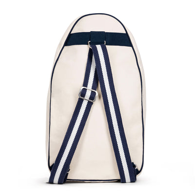 Back view of Hamptons pickleball sling bag. Bag has front mesh pocket and slip pocket on front to hold pickleball paddles. Bag has navy trim and navy and white striped straps. Bag has adjustable straps to be worn as a backpack or a crossbody.