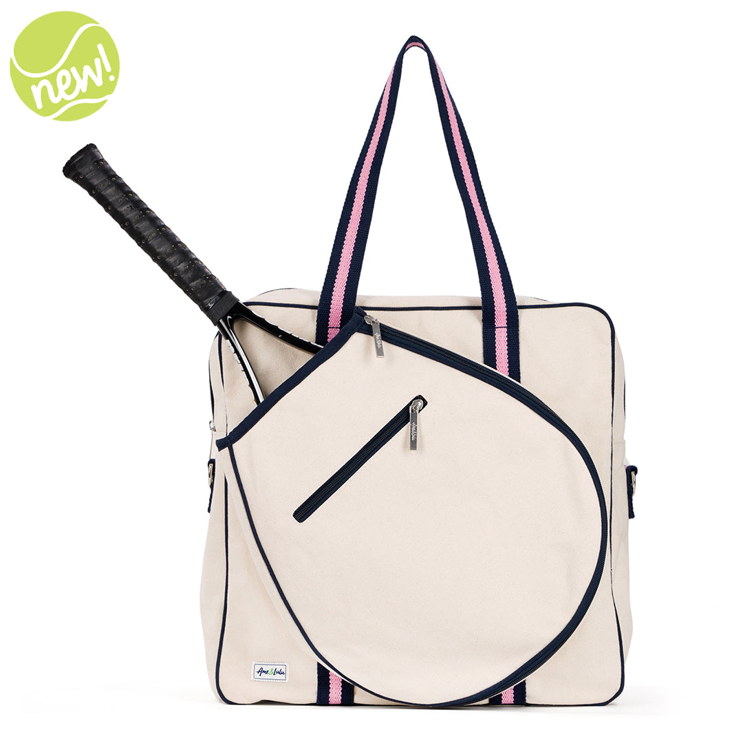 Natural canvas tennis tote with navy trim and navy and pink striped handles. Front pocket holds multiple tennis racquets.