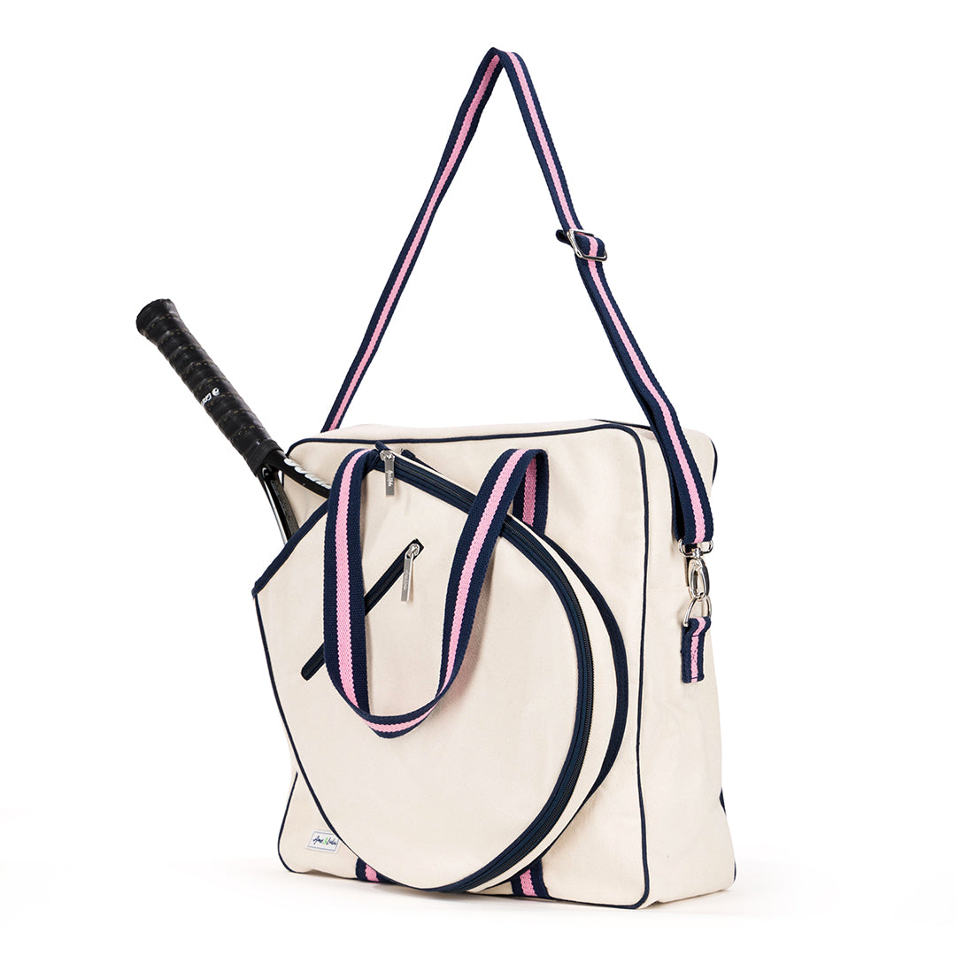 Natural canvas tennis tote with navy trim and navy and pink striped handles. Front pocket holds multiple tennis racquets.