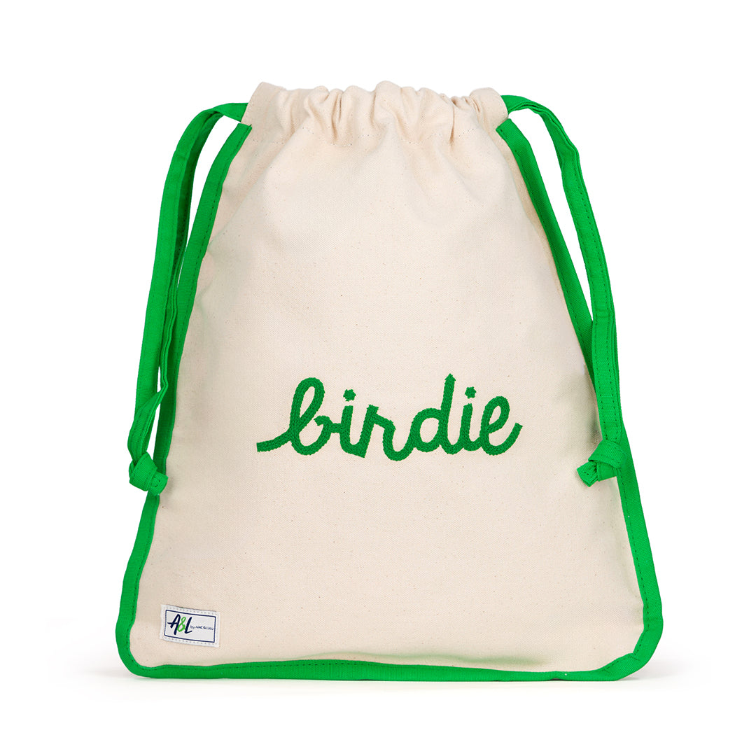 Front view of natural canvas shoe bag with green trim and the word "birdie" embroidered on the front in green.