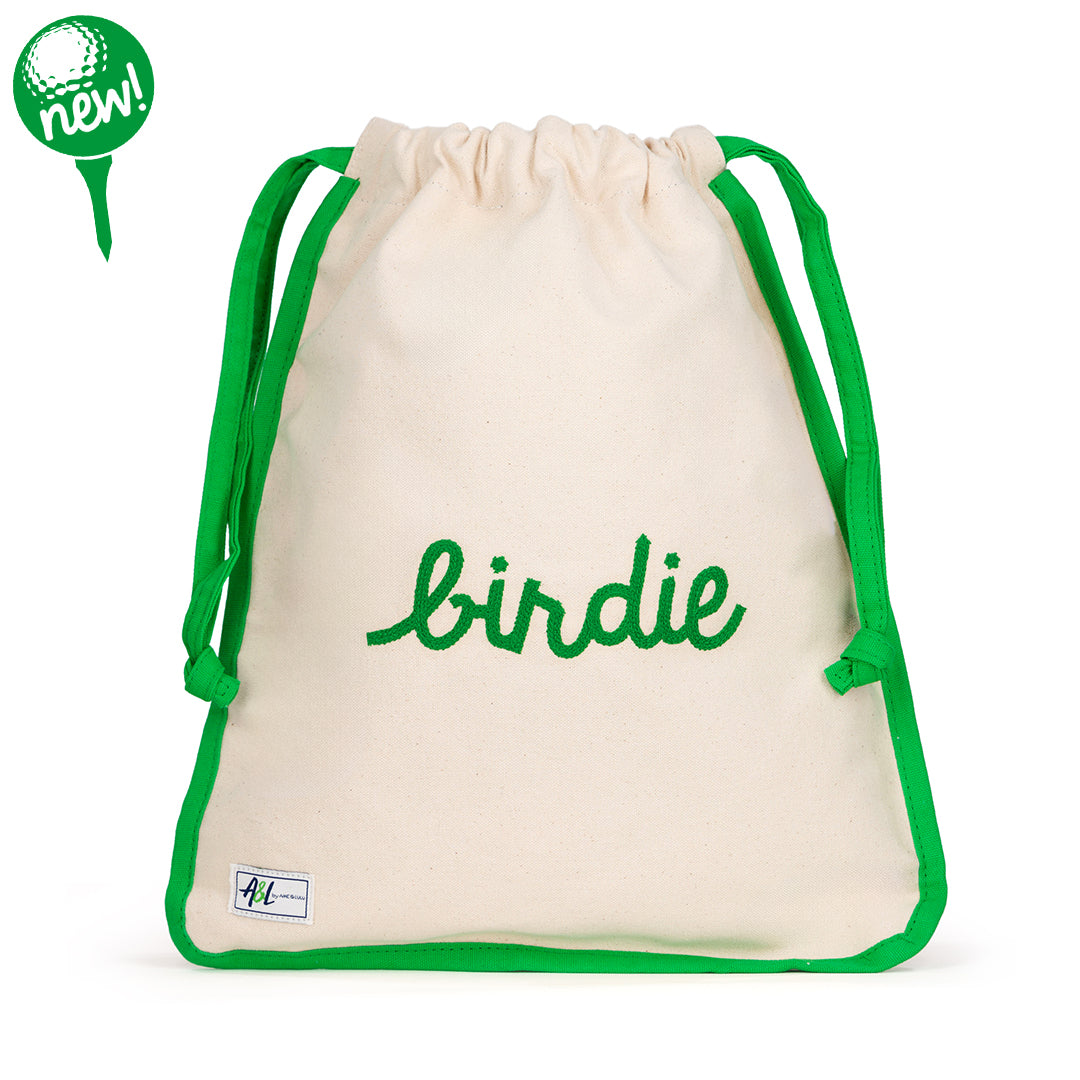 Front view of natural canvas shoe bag with green trim and the word "birdie" embroidered on the front in green.