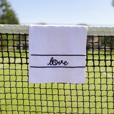 White terry towel laying flat on white background with navy stripes and the word love embroidered on it
