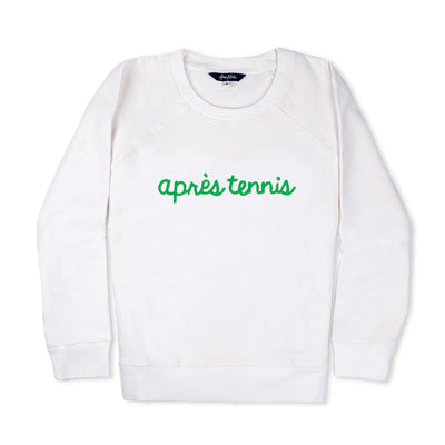 White sweatshirt lays flat on white background with green text reading apres tennis embroidered on the front