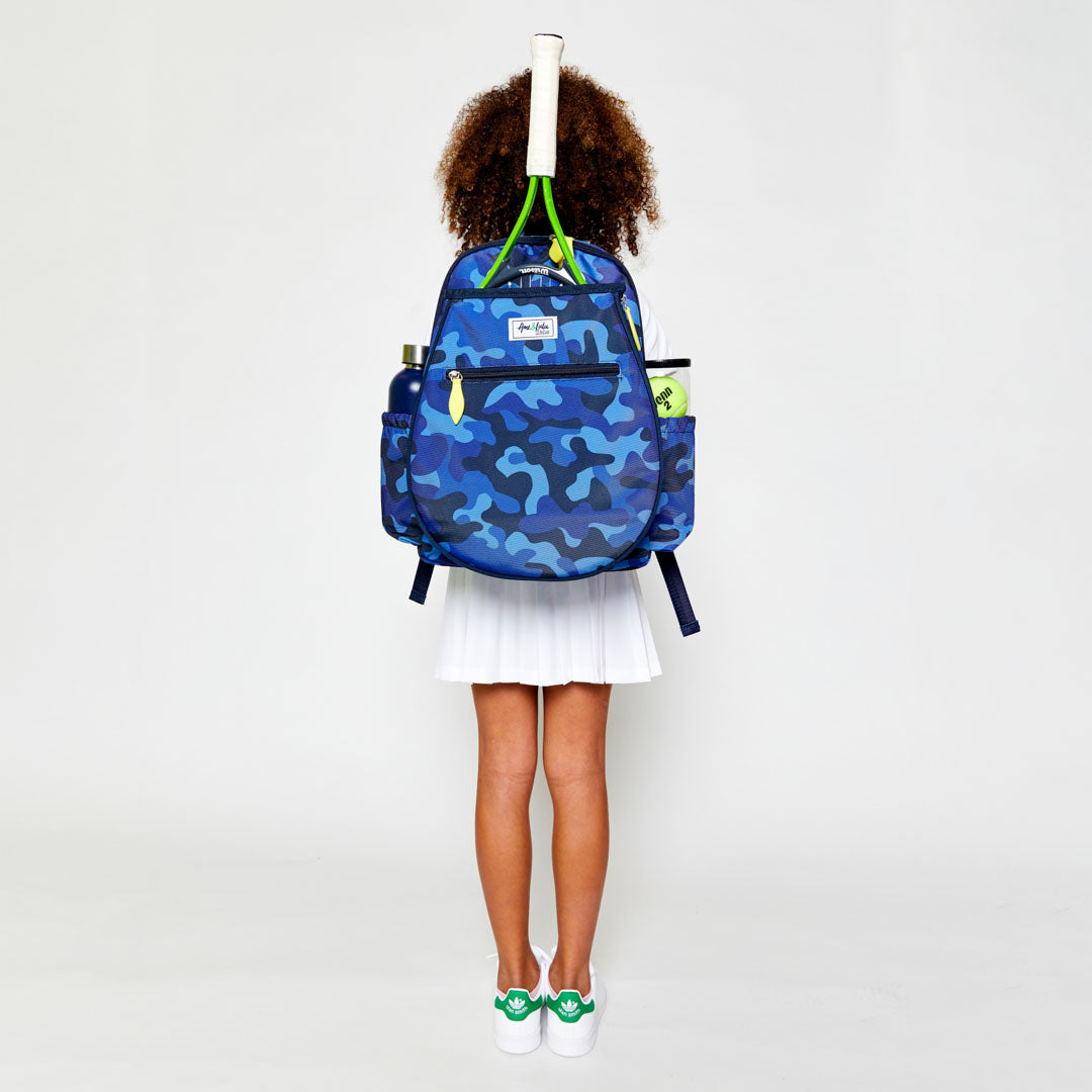 Little girl wearing navy camo kids tennis backpack with lime green zippers.