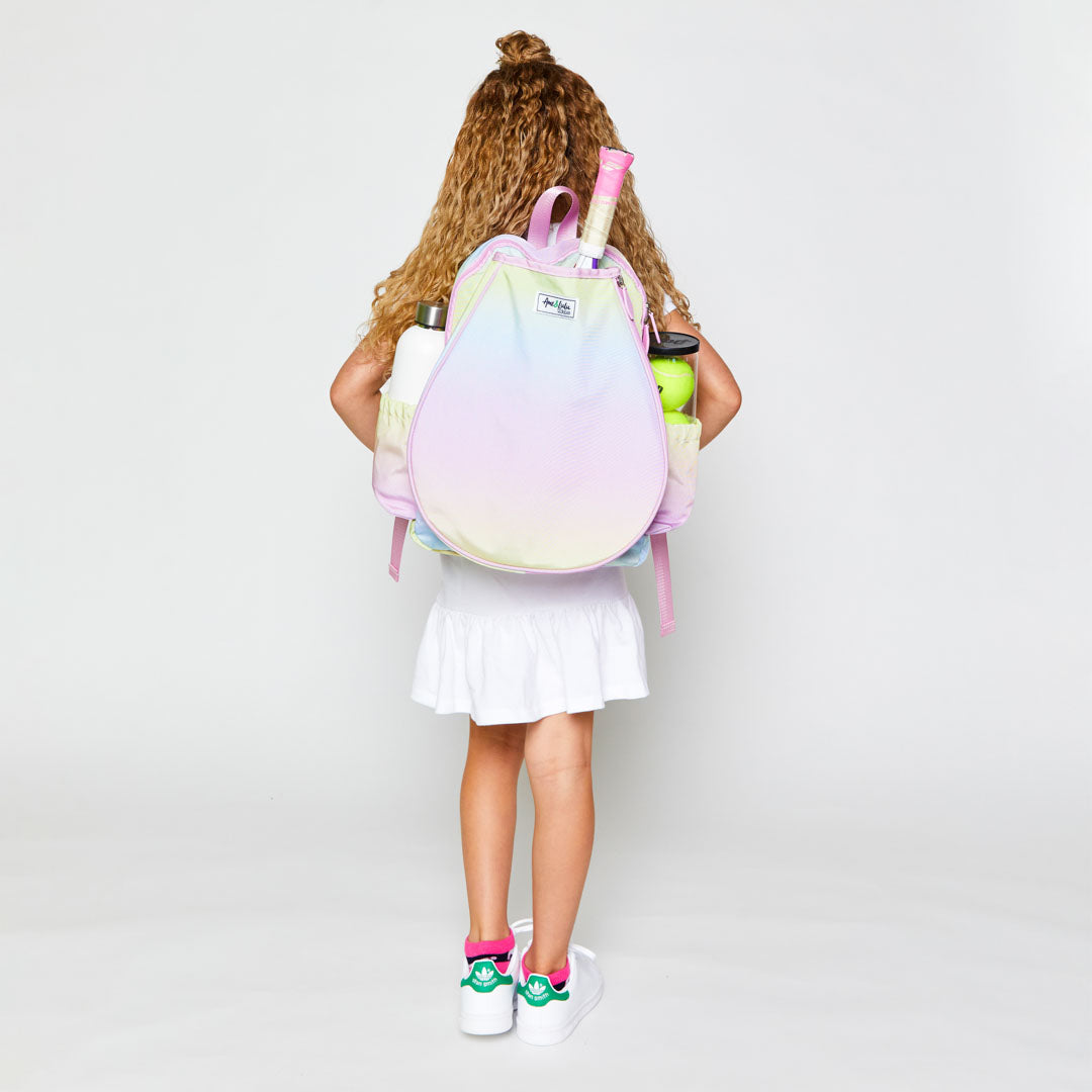 Little girl wearing rainbow ombre color kids tennis backpack.