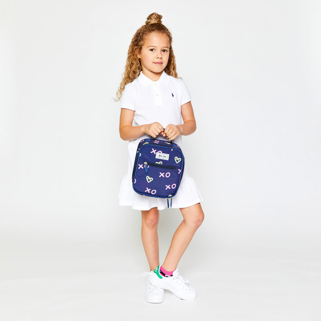 little girl holding navy kids lunch box with green heart shaped tennis ball pattern