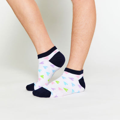girl wearing pair of white kids socks with navy heel and toes and rainbow hearts stitched on sock