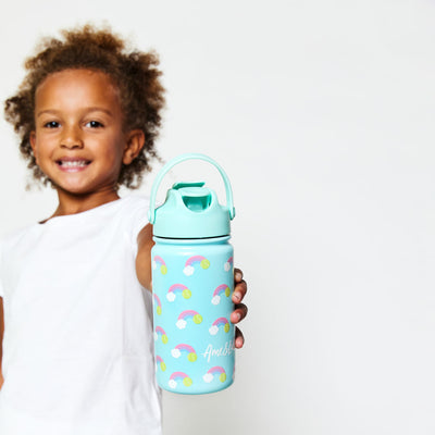 Little girl holding Light blue kids water bottle with rainbow and tennis ball pattern.