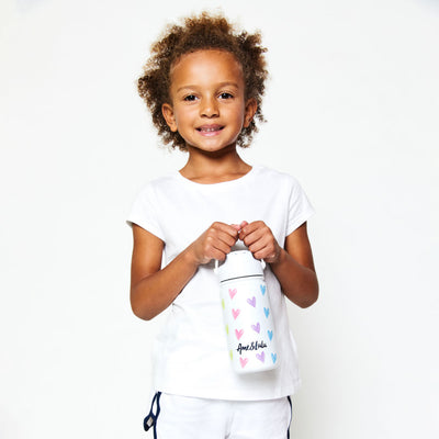 Little girl holding White kids water bottle with rainbow hearts pattern.