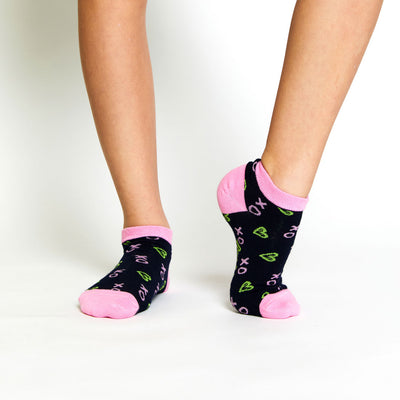 girl wearing pair of navy kids socks with pink heel and toes, and green heart shaped tennis balls