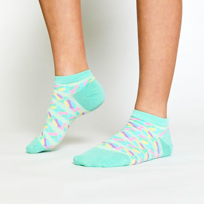 girl wearing pair of light green kids socks with pastel rainbow tennis balls stitched around socks