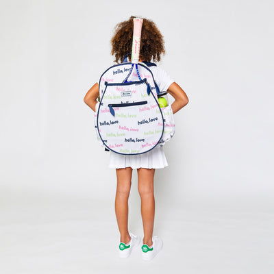 Little girl wearing a white kids tennis backpack with repeating patterns of the words hello love in pink green and navy.