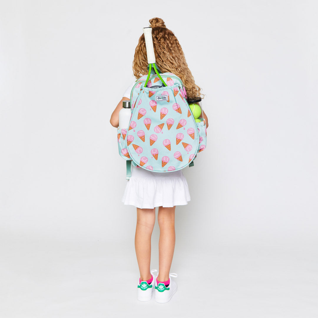 little girl stands wearing mint green kids tennis backpack with pink ice cream tennis balls pattern
