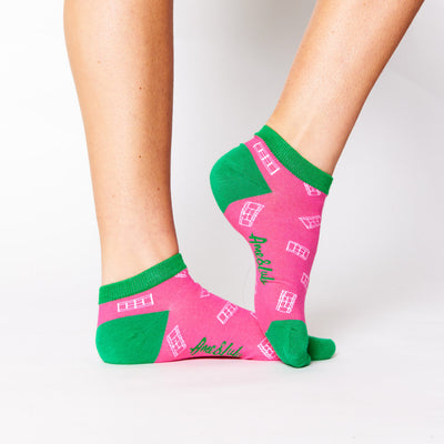 woman wears hot pink sock with green trim and white tennis court pattern