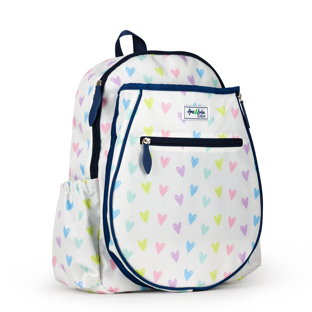 Side view of white kids tennis backpack with repeating pattern of rainbow hand drawn hearts.