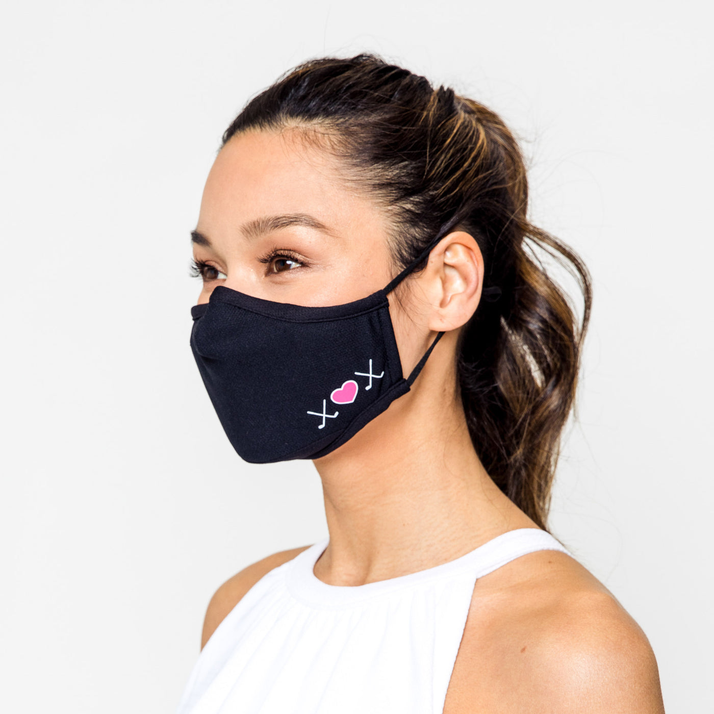 woman wearing black face mask with white and pink crossed golf clubs and heart printed on one side