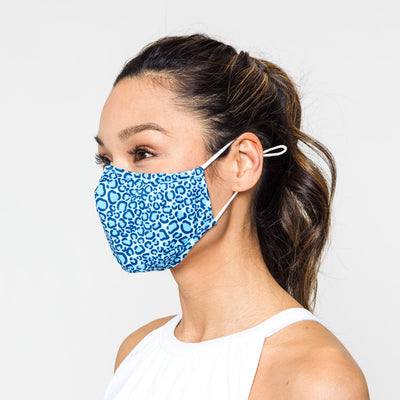 woman wears blue and navy leopard pattern face mask with white elastic straps