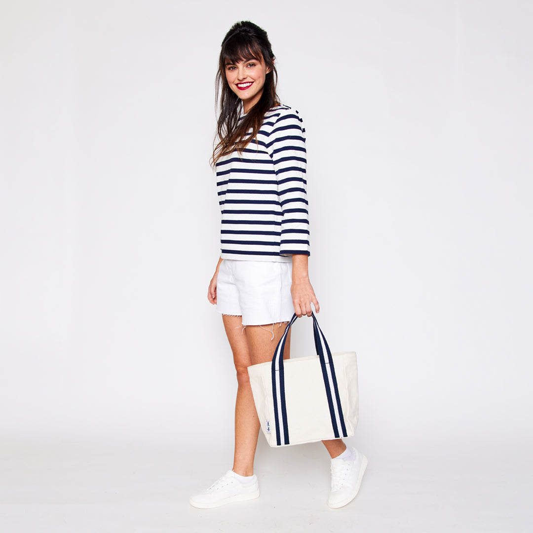 woman holding mini natural canvas tote with navy and white cotton webbing straps