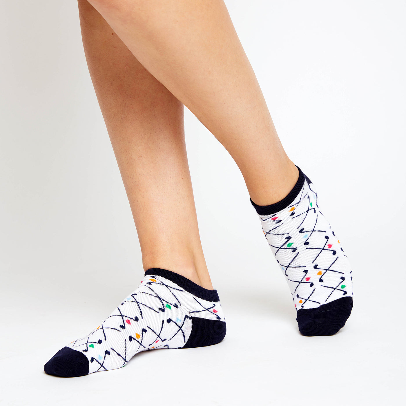 woman wears white socks with pattern of navy crossed golf clubs and rainbow hearts
