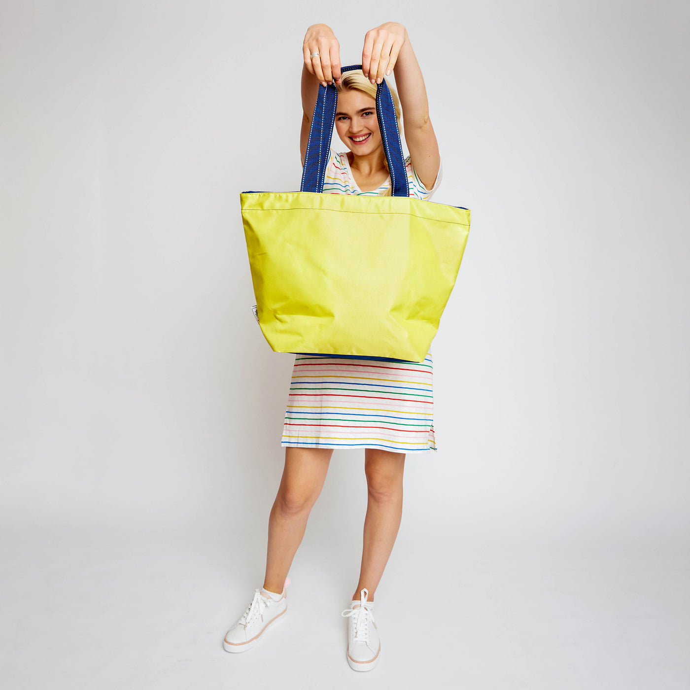 woman holding yellow nylon tote bag in front of her