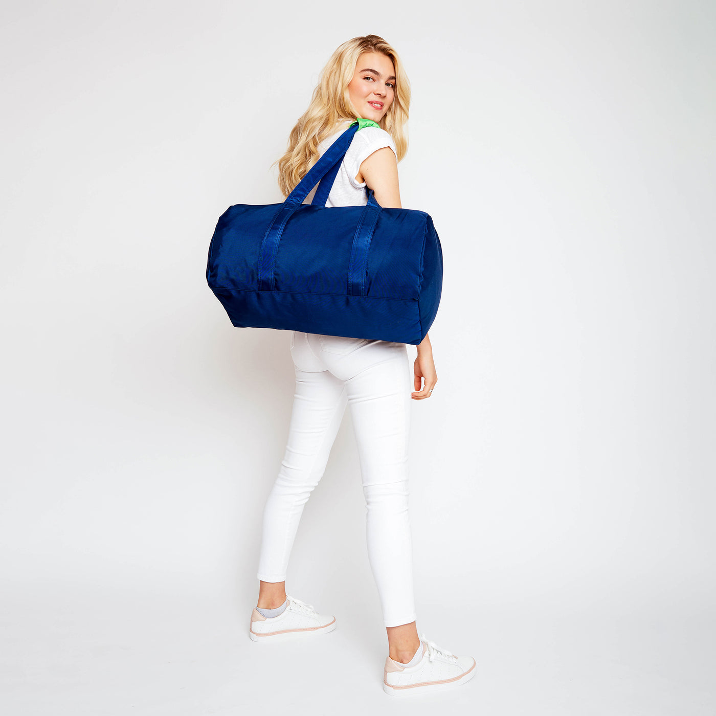 woman holding navy nylon duffel over her shoulder