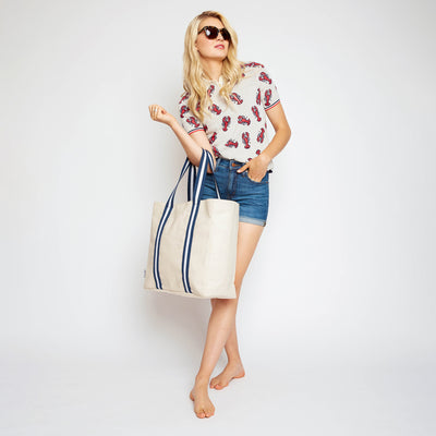 woman holding natural canvas tote with navy and white cotton webbing straps