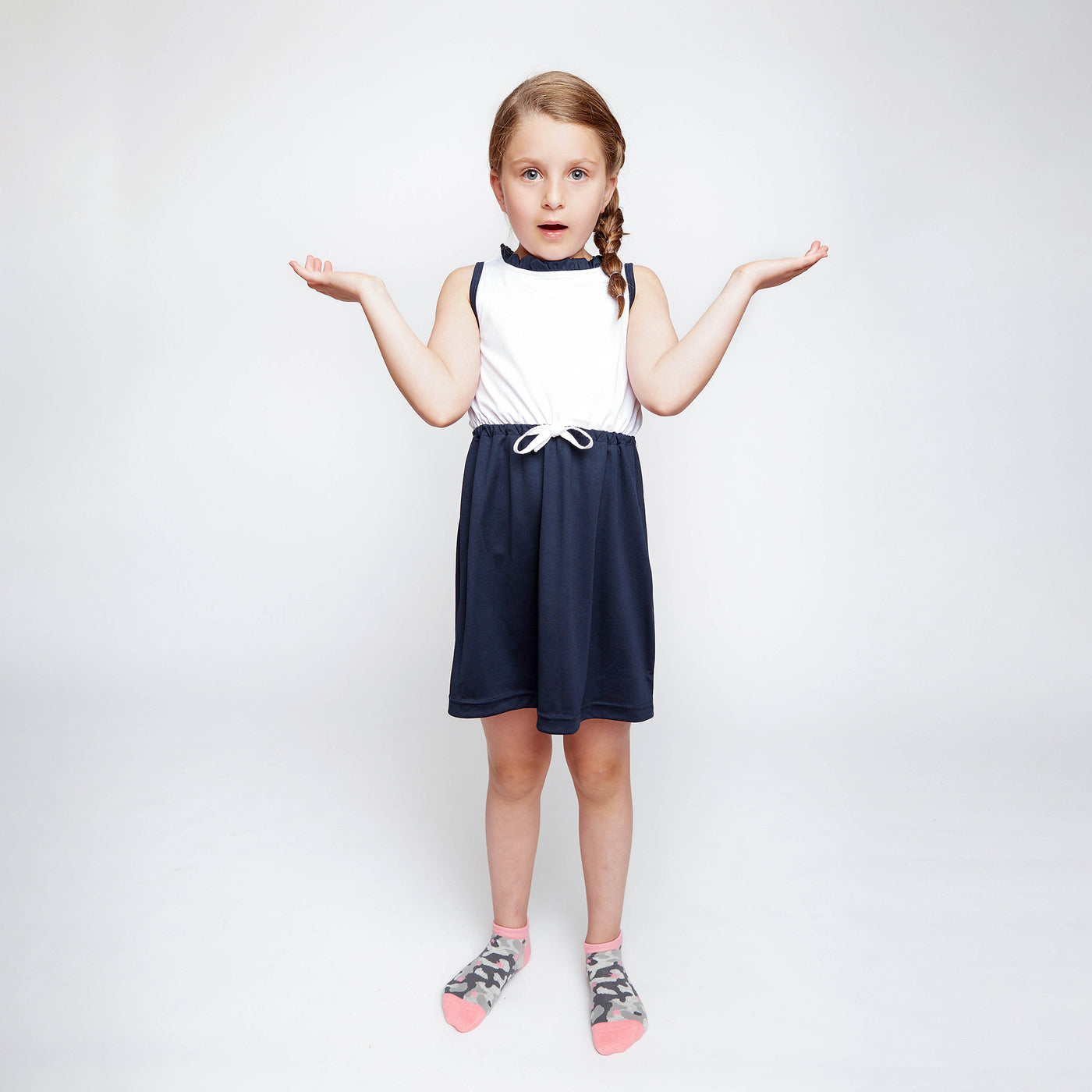 little girl raising her arms and wearing pair of grey camo kids socks with light pink heel and toes, and pink stars stitched on to socks