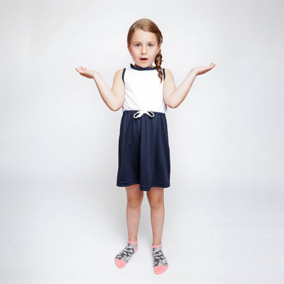 little girl raising her arms and wearing pair of grey camo kids socks with light pink heel and toes, and pink stars stitched on to socks