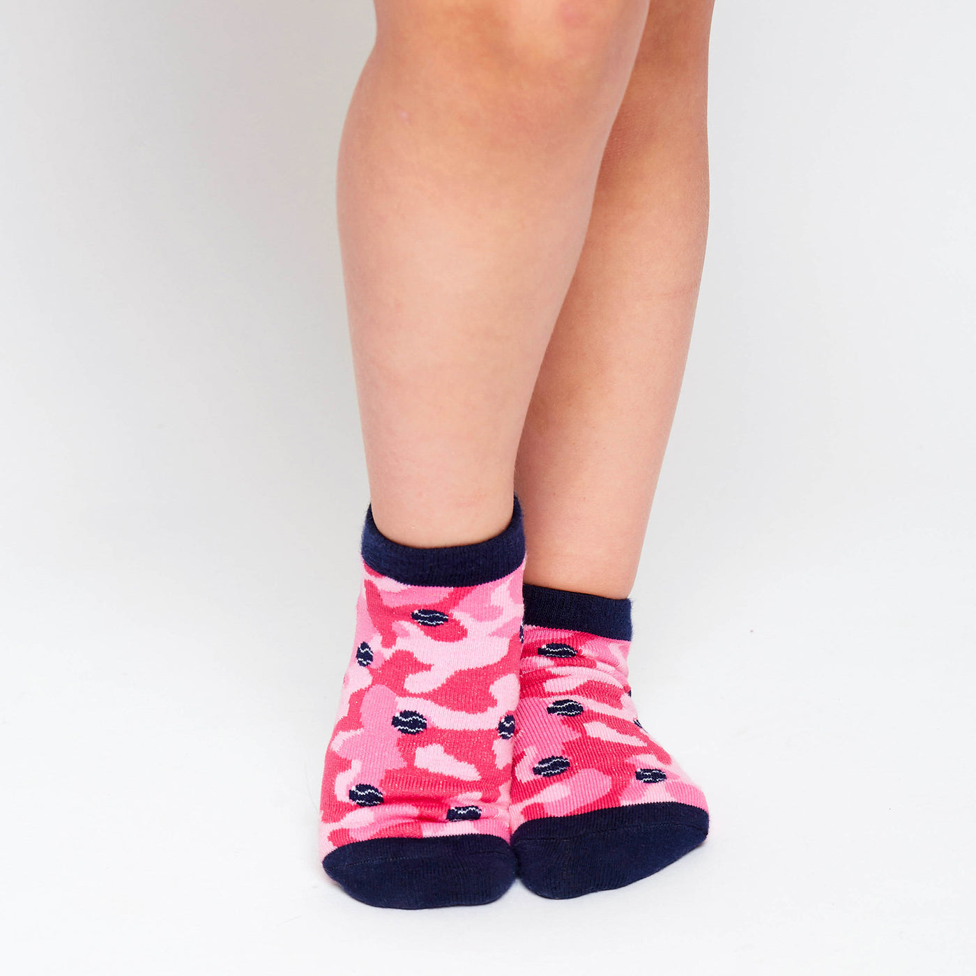 girl wearing pair of hot pink camo kids socks with navy heel and toes, and navy tennis balls stitched on socks