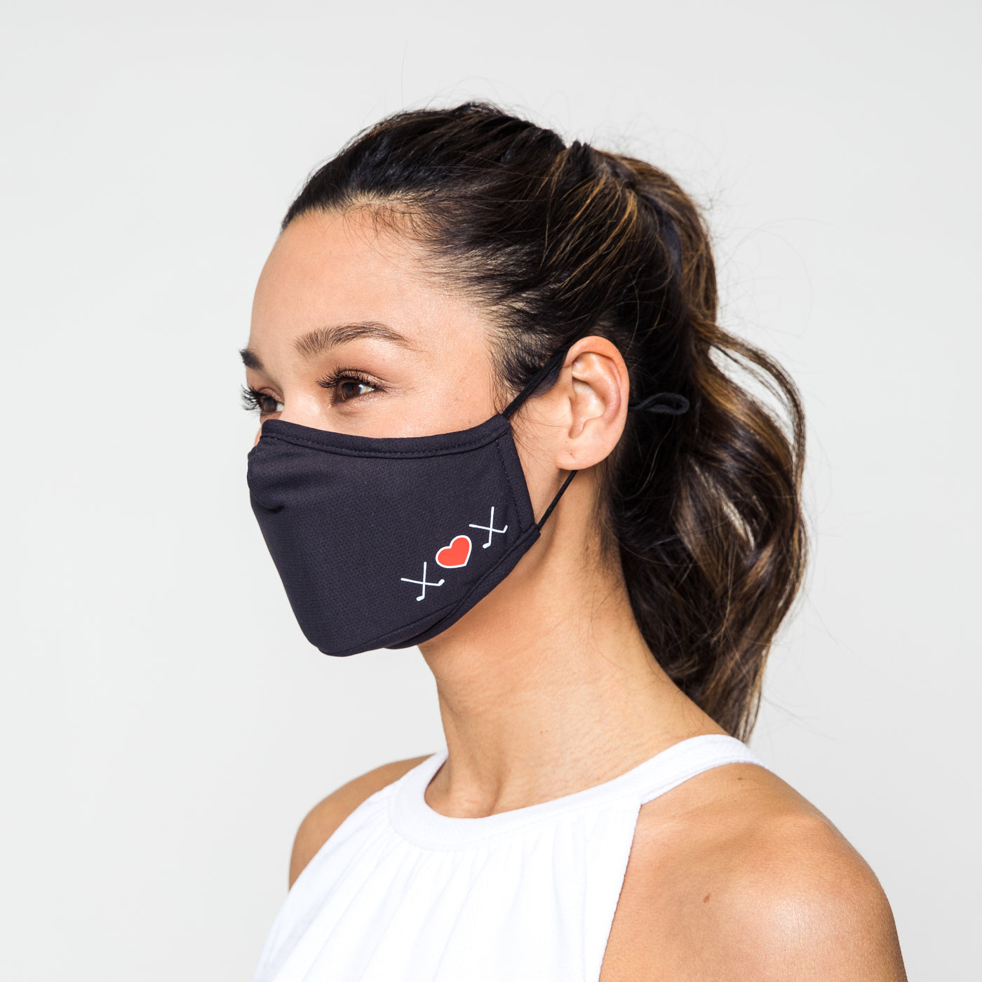 woman wearing charcoal grey face mask with white crossed golf clubs and red heart printed on one side