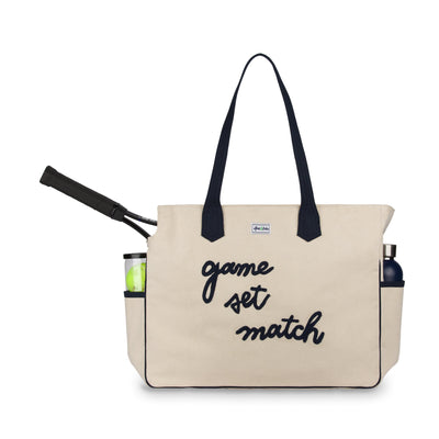 Front view of love all court bag. Large canvas tennis tote with the phrase "game set match' embroidered in a cursive font across the front of the bag.
