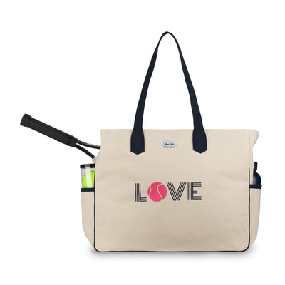 Front view of love all court bag. Canvas tennis tote with side pockets holding water bottle and tennis balls. Front of bag reads the word love, with the letter O made out of a hot pink tennis ball.