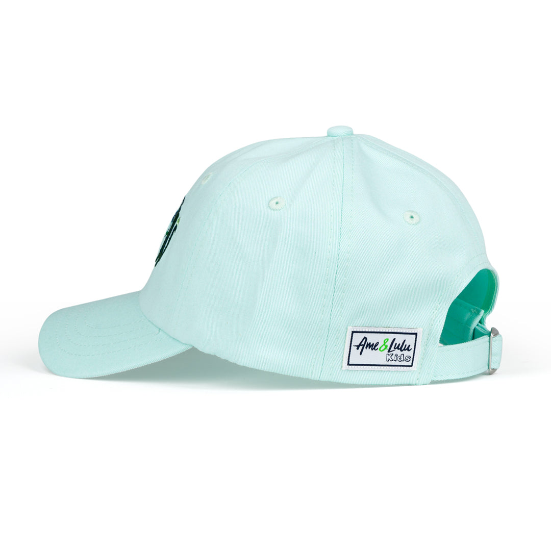 side view of light blue kids baseball hat with alligator playing tennis embroidered on the front