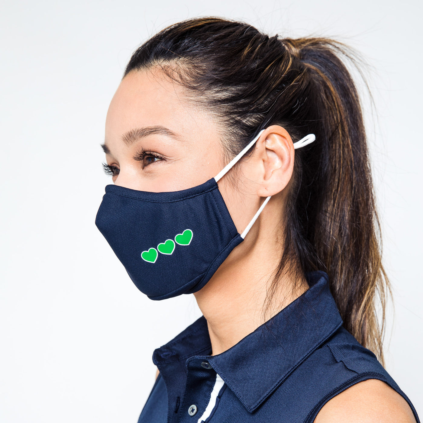 woman wearing a Navy face mask with green hearts printed on one side