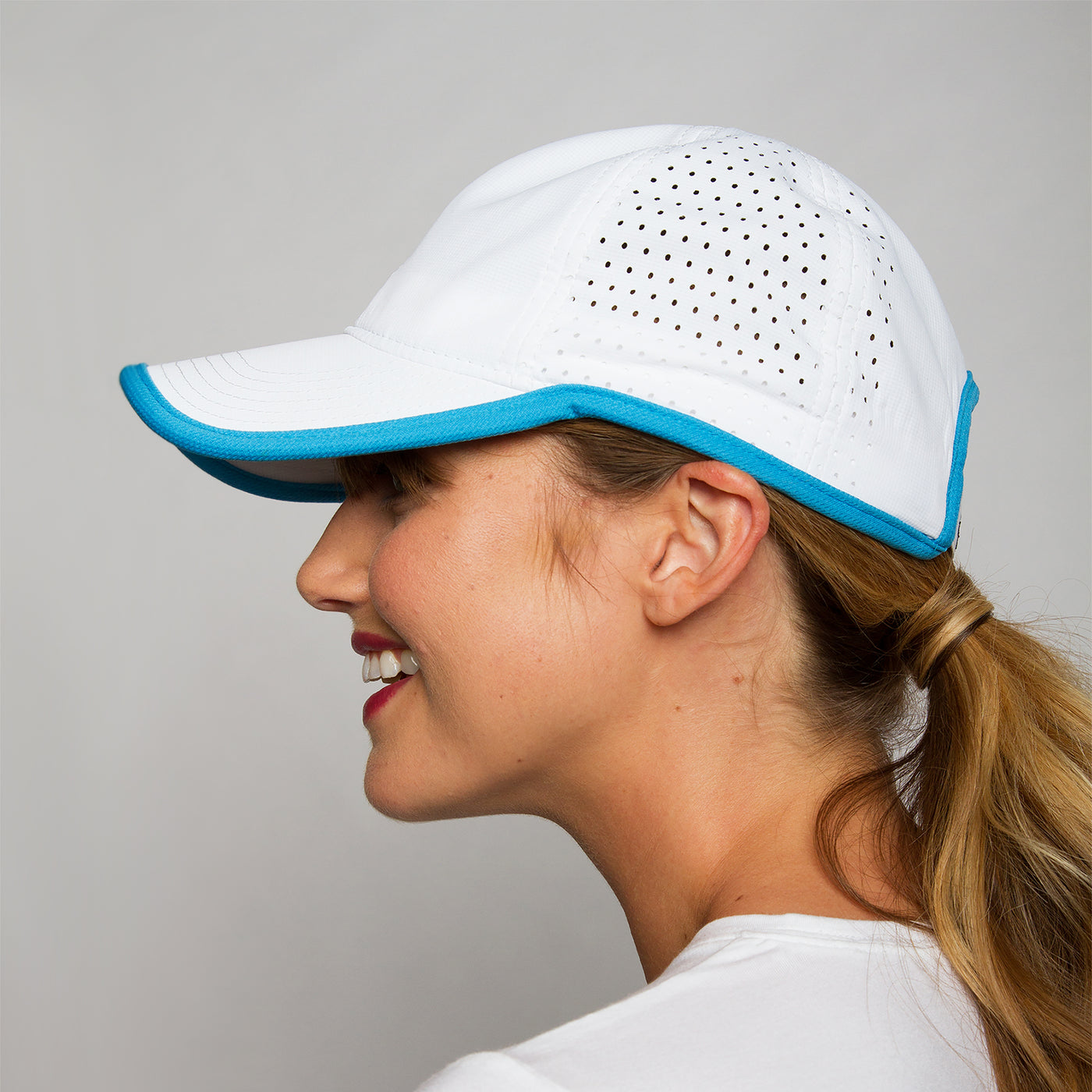 woman wears white sport hat with blue trim.