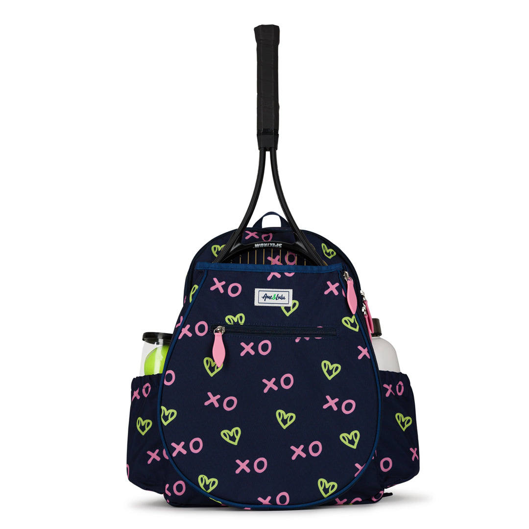 Front view of navy kids tennis backpack with repeating green heart shaped tennis balls and pink x and o.