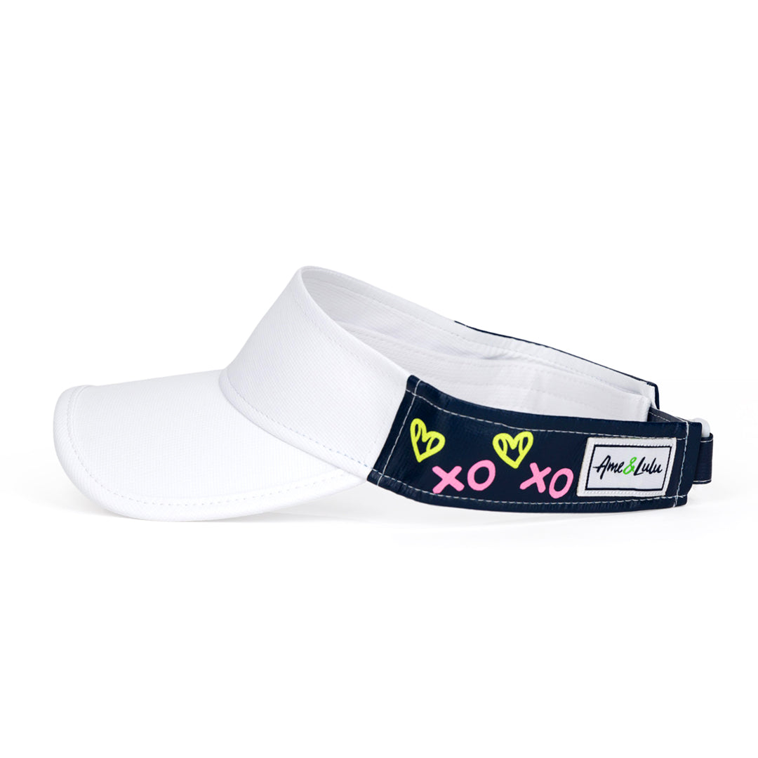 Side view of navy kids visor with green heart shaped tennis balls and pink x and o printed on the sides.