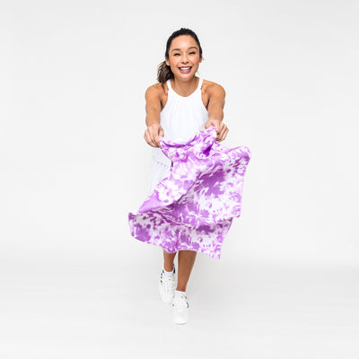 Woman waves infront of her a Lavender purple tie dye rectangular towel with purple trim