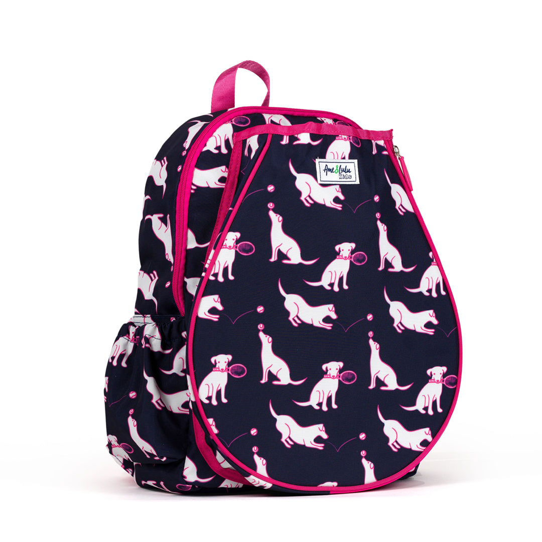 side view of navy kids tennis backpack with hot pink trim and pattern of white puppies holding tennis racquets and tennis balls