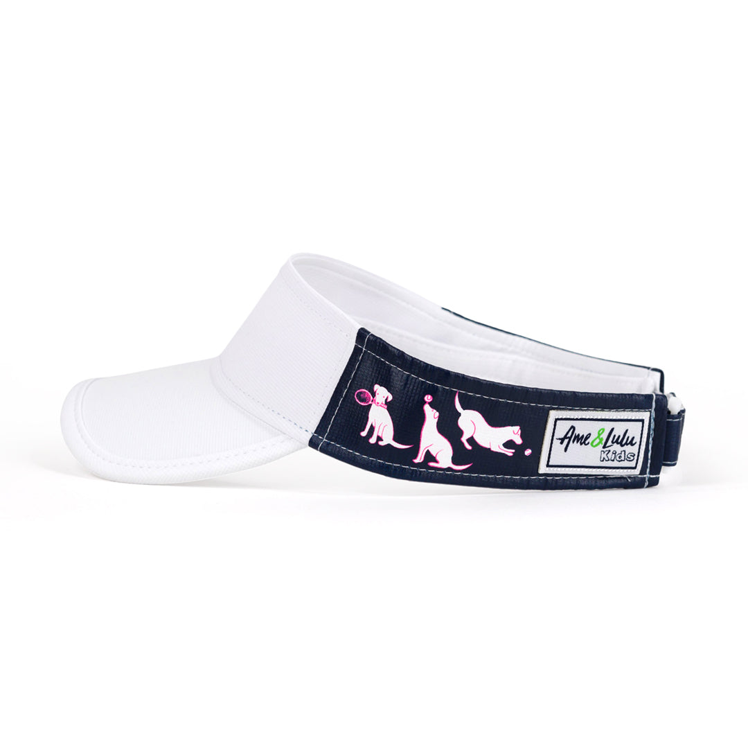 Side view of navy kids visor with white and pink puppies playing tennis on the sides.